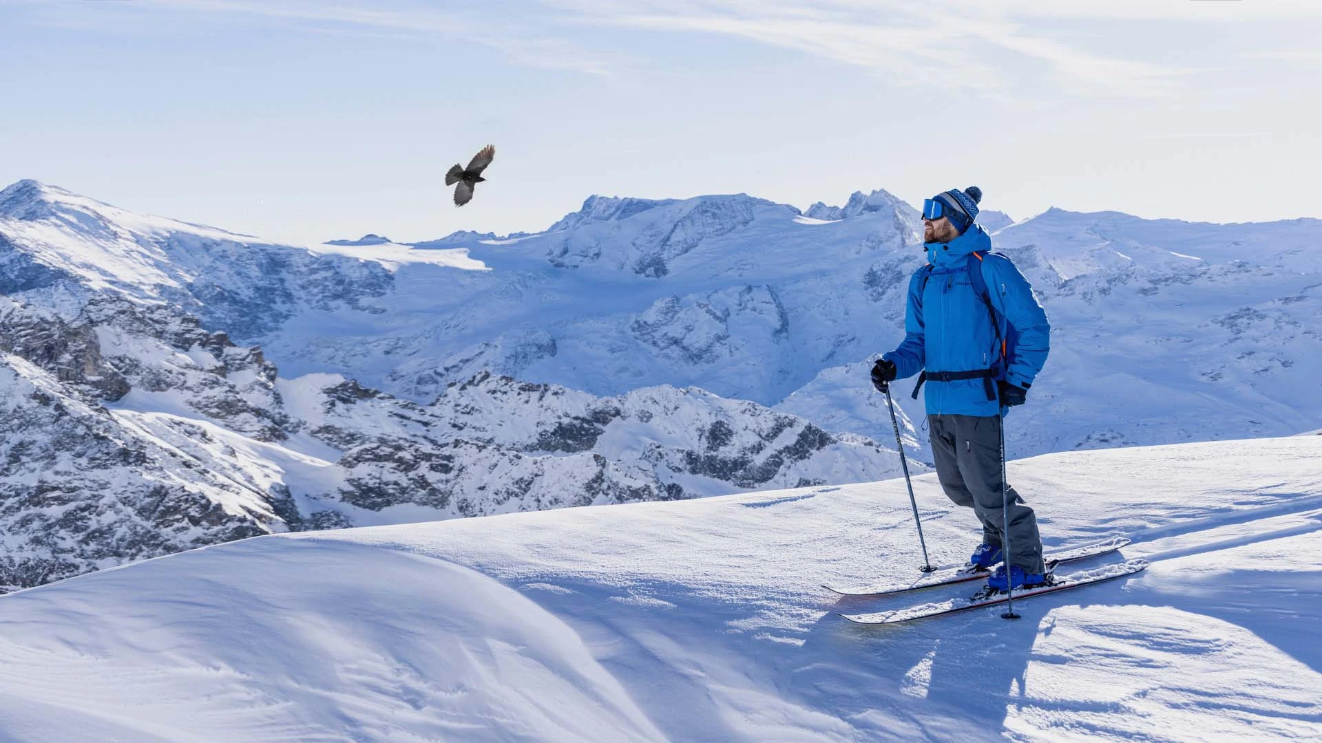 Man skiing on the top of a mountain with a clear blue sky